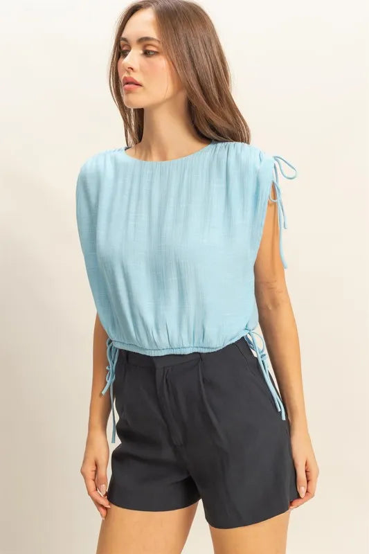 Trendsi HYFVE sleeveless blouse with bubble hem, side tie detail, and round neck, featuring a stylish and casual design.