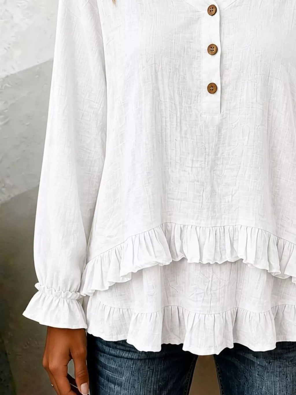 Long sleeve blouse with ruffled hem in soft fabric, displayed on a hanger, from Trendsi, showcasing its stylish design and details.