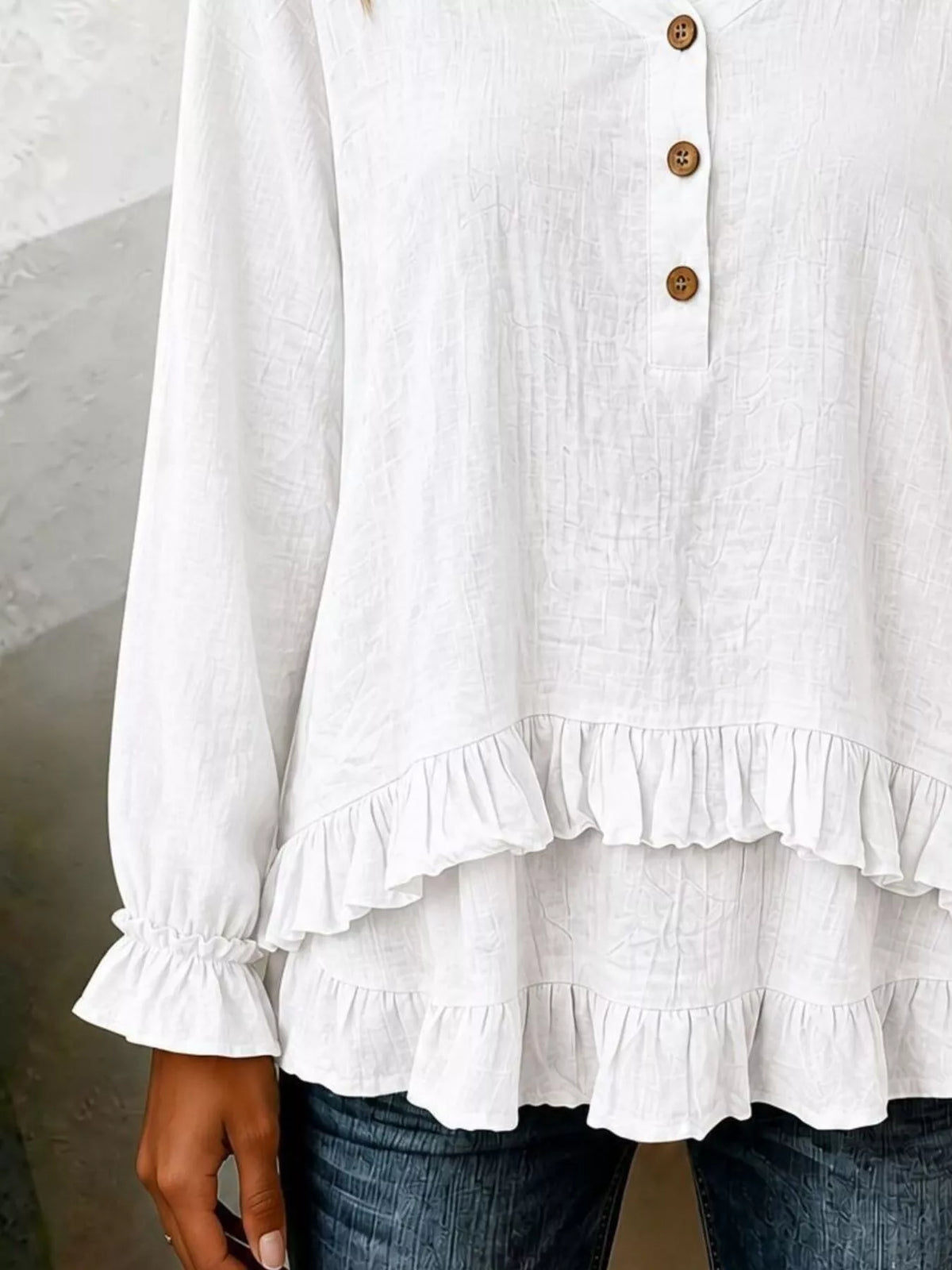 Long sleeve blouse with ruffled hem in soft fabric, displayed on a hanger, from Trendsi, showcasing its stylish design and details.