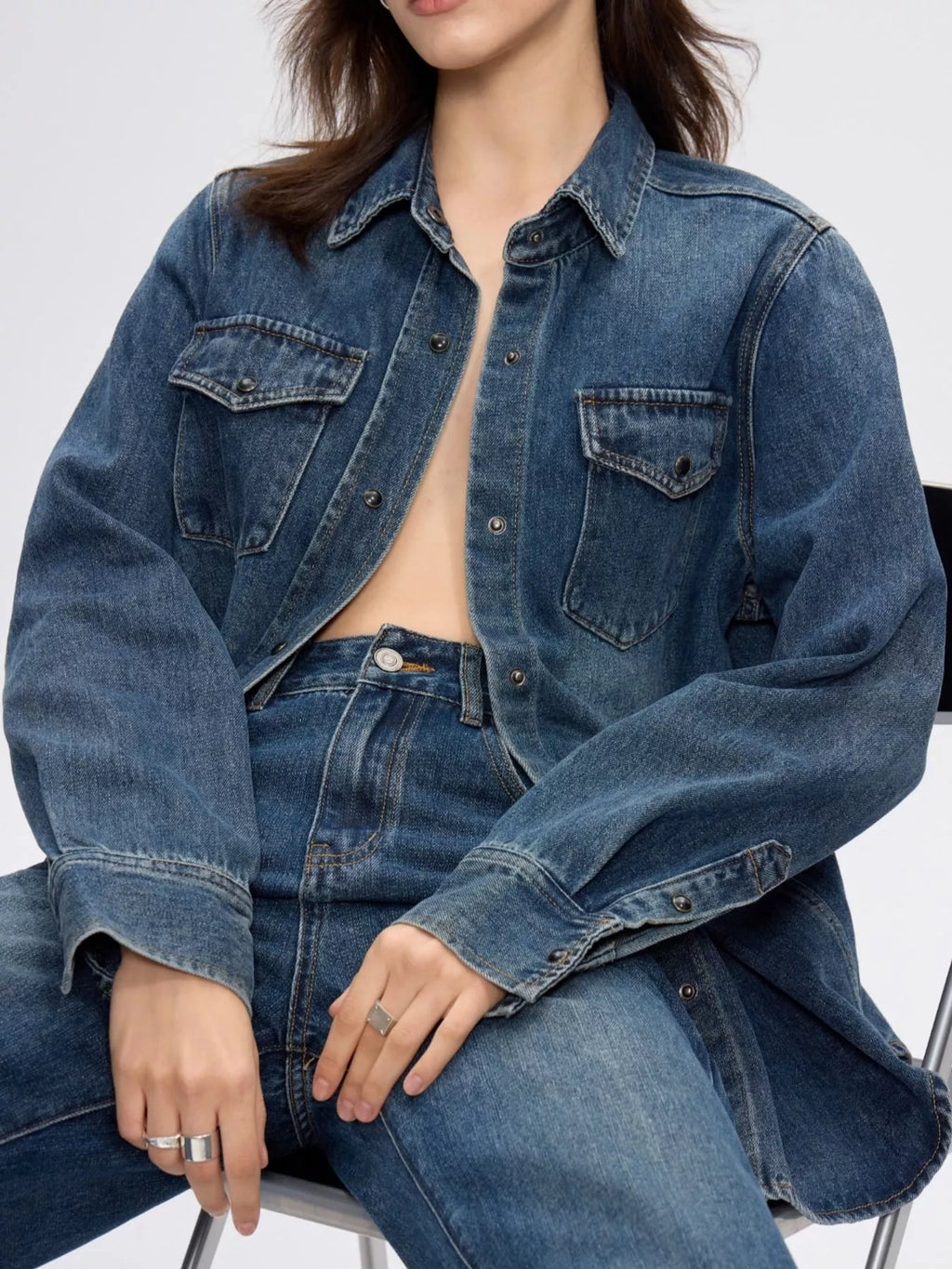 Long-sleeve denim shirt with snap-down front from Trendsi, displayed on a hanger showcasing classic blue denim and button details.