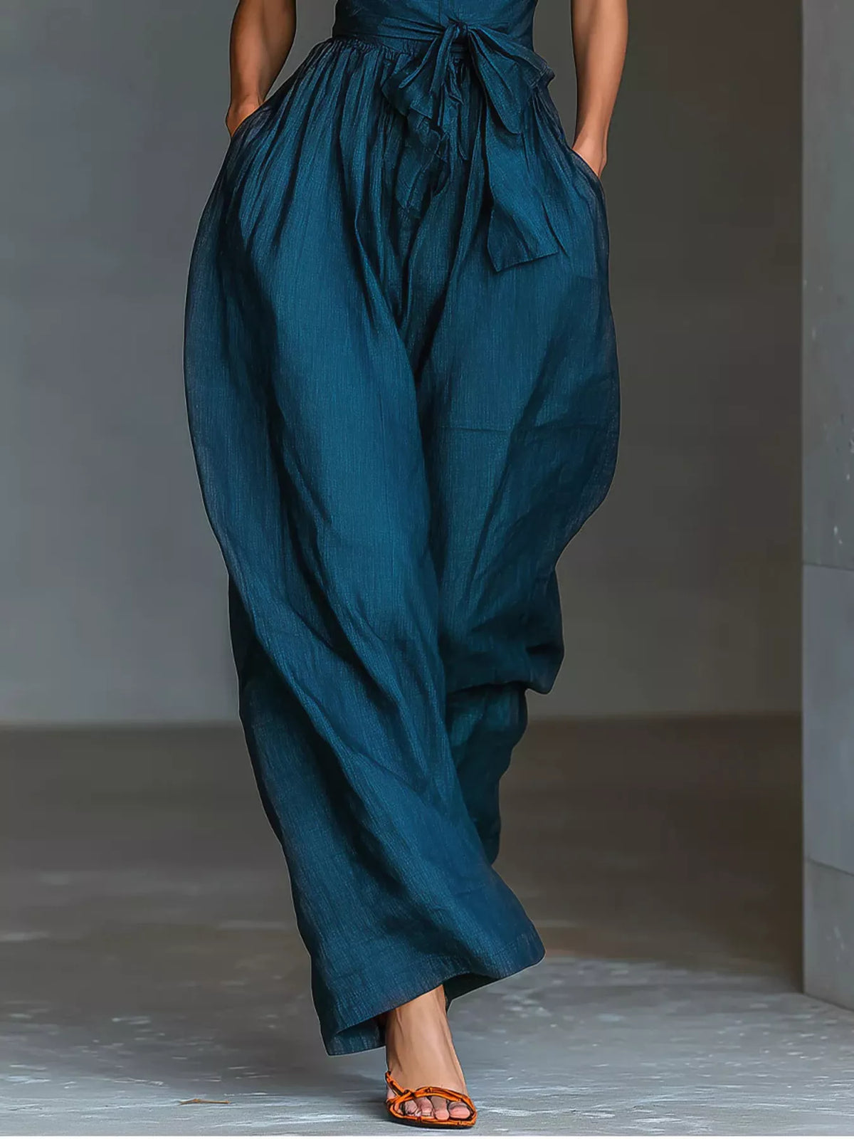 Halter neck wide-leg jumpsuit with waist-tie detail, stylish women's fashion from Trendsi, shown in black fabric with flowing silhouette.