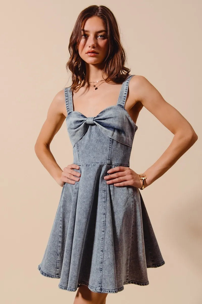 Mineral washed bow ribbon denim flare dress by Trendsi featuring a fitted bodice and flowing skirt, styled with a bow detail at the waist.