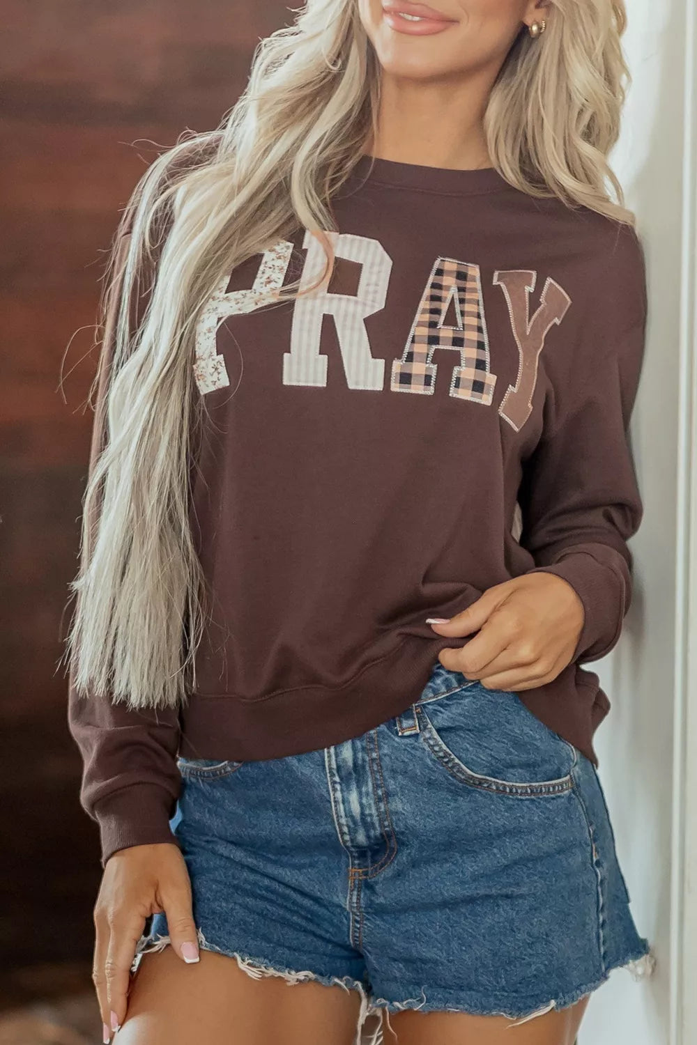 Dark brown crewneck sweatshirt with plaid PRAY graphic