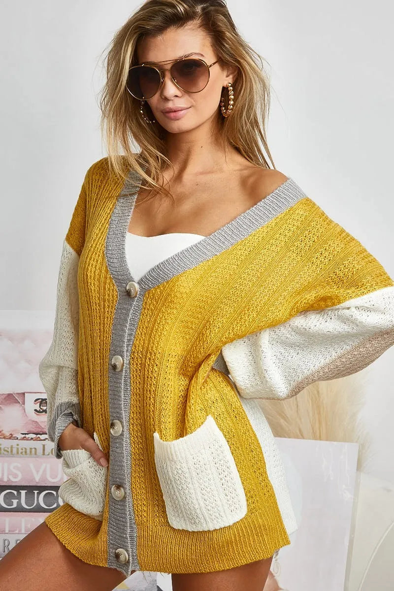 Color block sweater cardigan with button closure from Trendsi, featuring a stylish, cozy knit design and vibrant color segments.