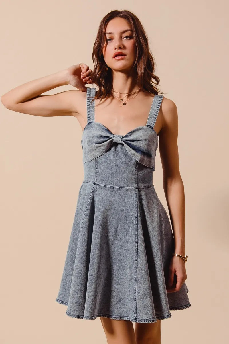 Mineral washed bow ribbon denim flare dress by Trendsi featuring a fitted bodice, bow detail, and flowing skirt.