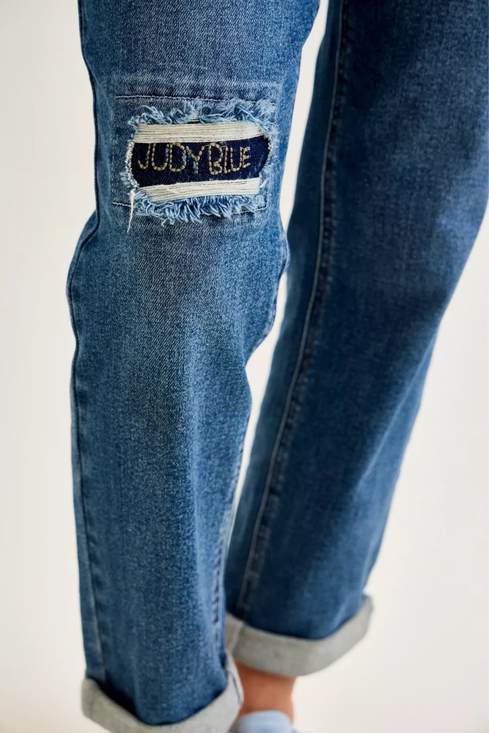 Light blue Judy Blue mid-rise boyfriend jeans with embroidered repair patches and distressed details, styled with casual fit.